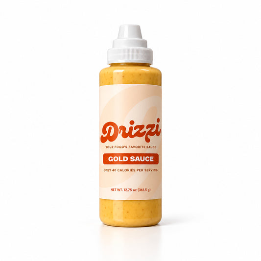 A squeeze bottle of Drizzi Gold Sauce on a clean white background. The bottle is filled with a golden yellow-orange sauce and features a white cap and a cream-colored label with orange branding.